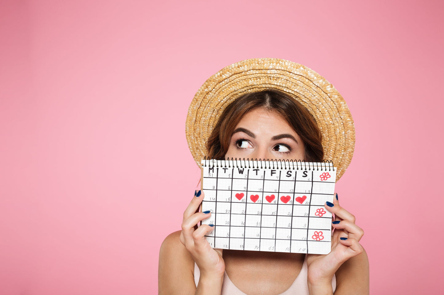 Frau mit Strohhut mit Periodenkalender in der Hand auf pinken Hintergrund 