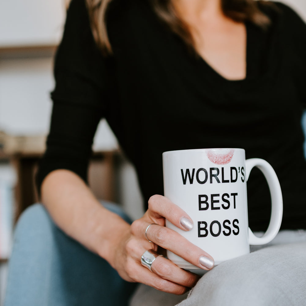 Sitzende Business Frau mit Worlds best boss Tasse in der Hand 