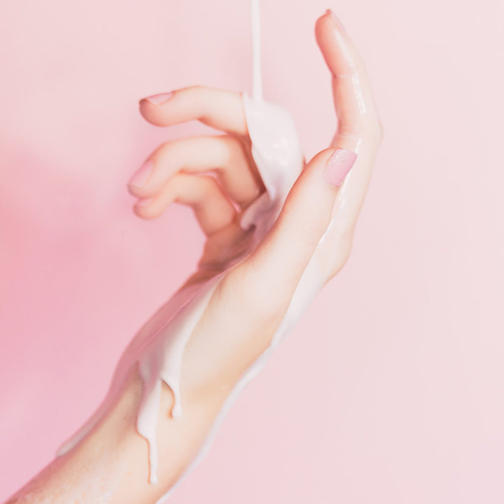 Frauenhand auf rosafarbenen Hintergrund mit cremigen Schleim Flüssigkeit auf Hand