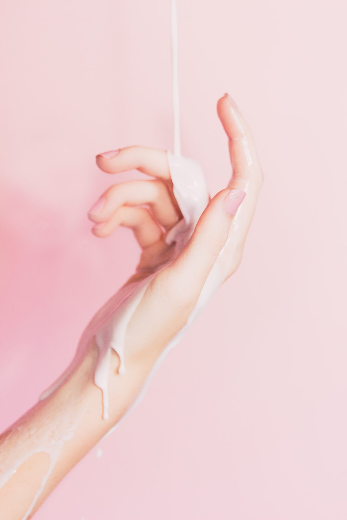 Frauenhand auf rosafarbenen Hintergrund mit cremigen Schleim Flüssigkeit auf Hand